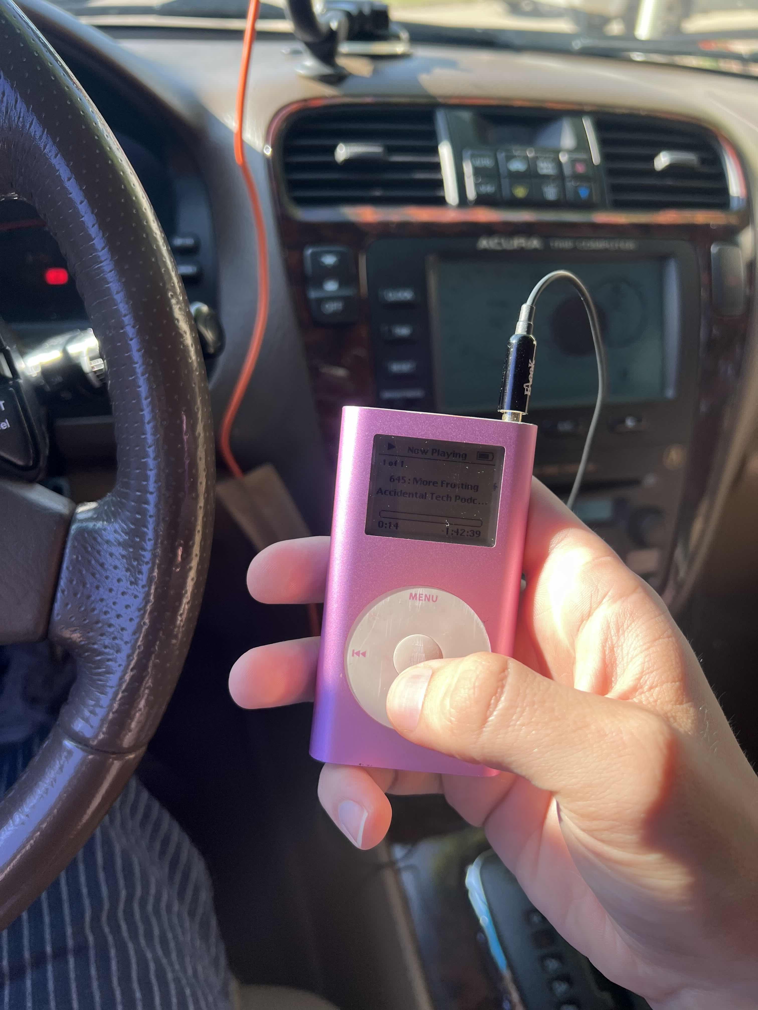 An iPod held in a hand inside a car