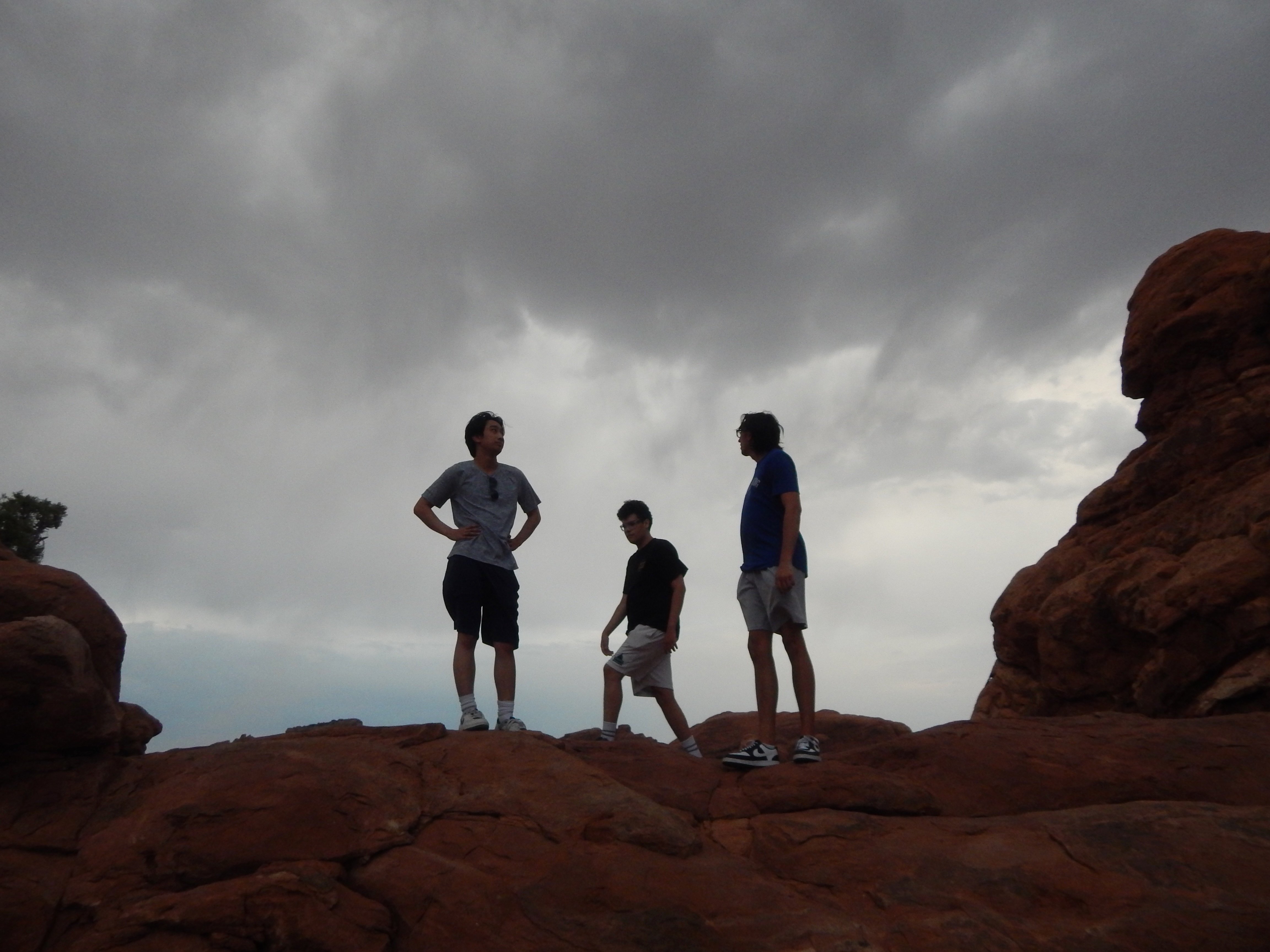 three figures in low light underneath an arch