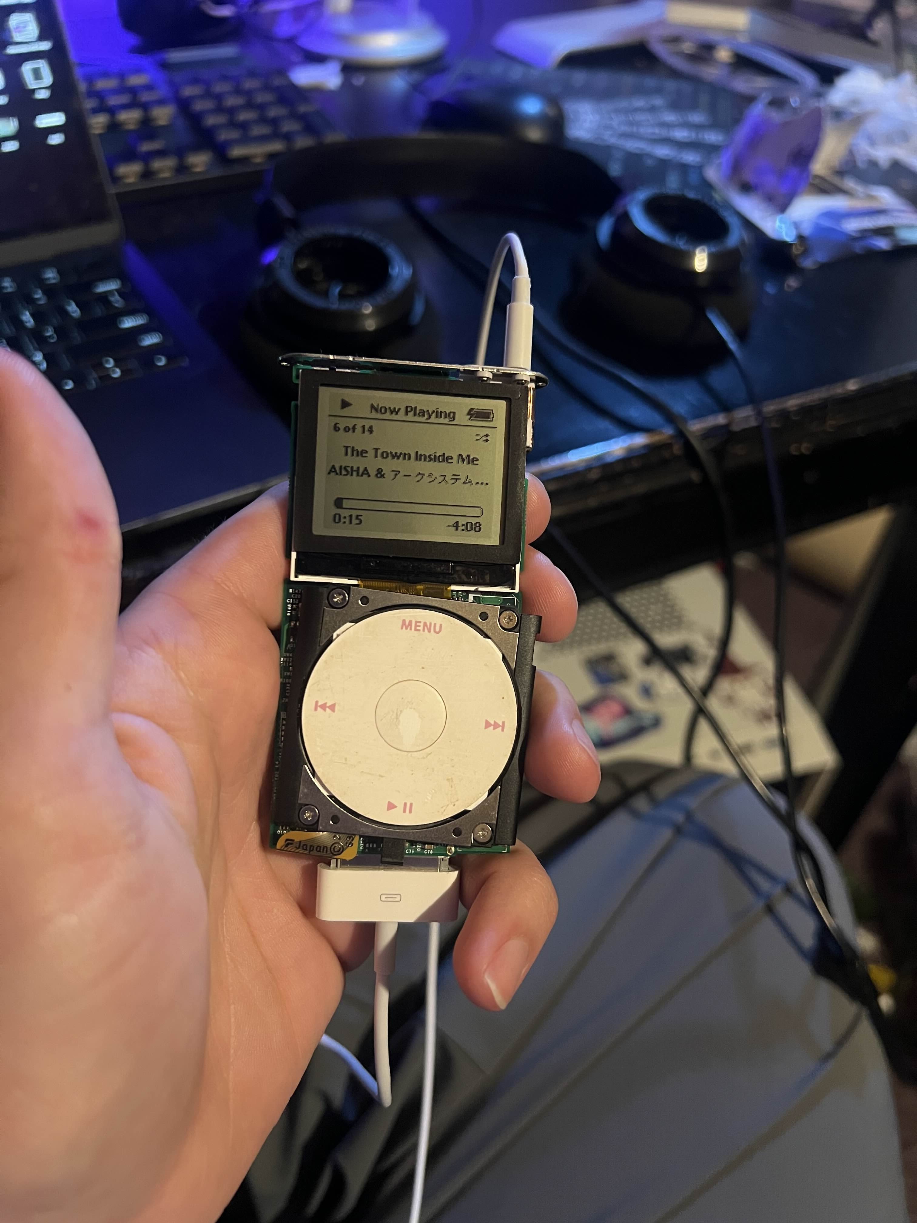 An iPod held in a hand without its shell playing 'The Town Inside Me'